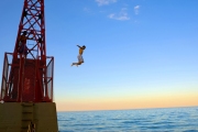 Action of young boys jumping off a buoy on Lake Michigan.  Chicago photographer Alex Garcia