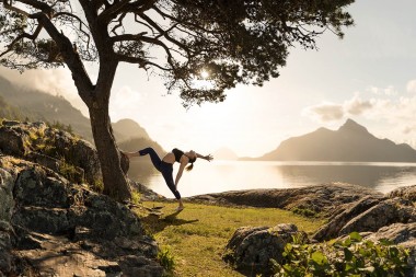 RodMcLean_Women-doing-yoga-backbend-with-sun-near-water_TGG